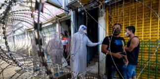 Malaysian health worker in PPE behind barbed wire fence | LiCAS.news